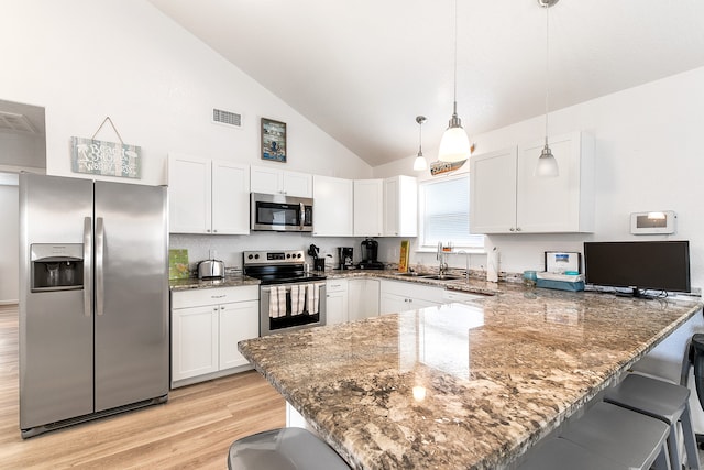 kitchen featuring hanging light fixtures, a breakfast bar area, appliances with stainless steel finishes, and light hardwood / wood-style floors