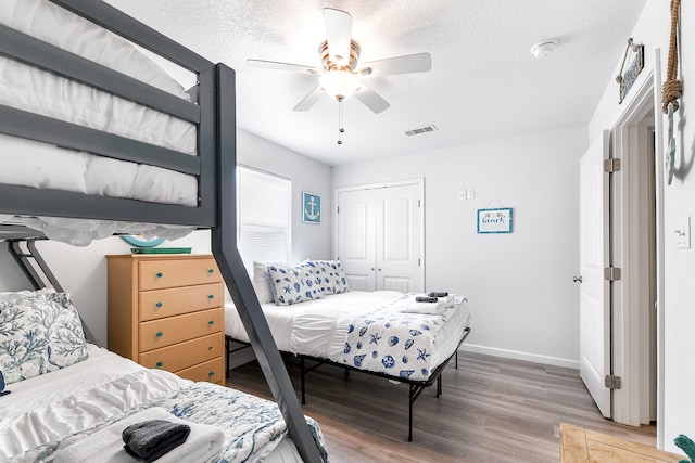 bedroom with ceiling fan, a textured ceiling, hardwood / wood-style floors, and a closet