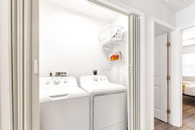 clothes washing area featuring washer hookup, hookup for an electric dryer, independent washer and dryer, and light hardwood / wood-style flooring