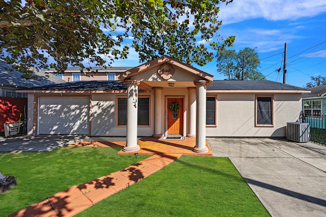 view of front of house with a garage, a front lawn, and central AC