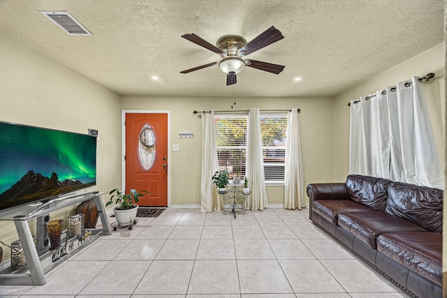 living room with a textured ceiling, light tile patterned floors, and ceiling fan