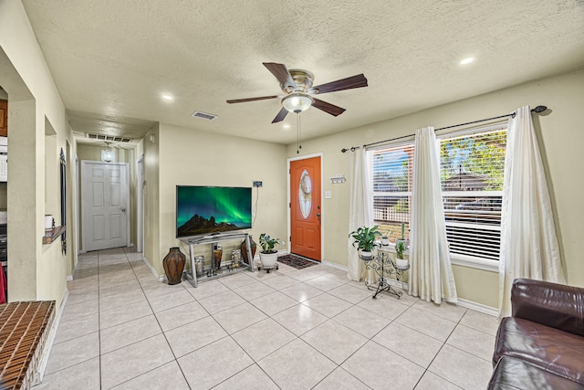 living room with ceiling fan, a textured ceiling, and light tile patterned floors