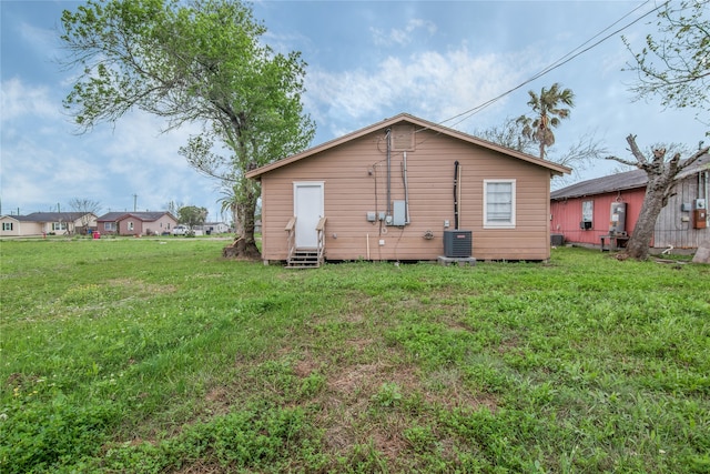 back of property featuring central AC and a yard