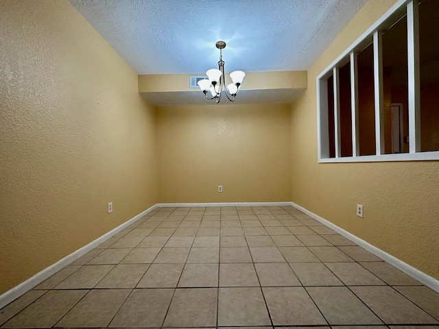 unfurnished room featuring an inviting chandelier, a textured ceiling, and light tile floors