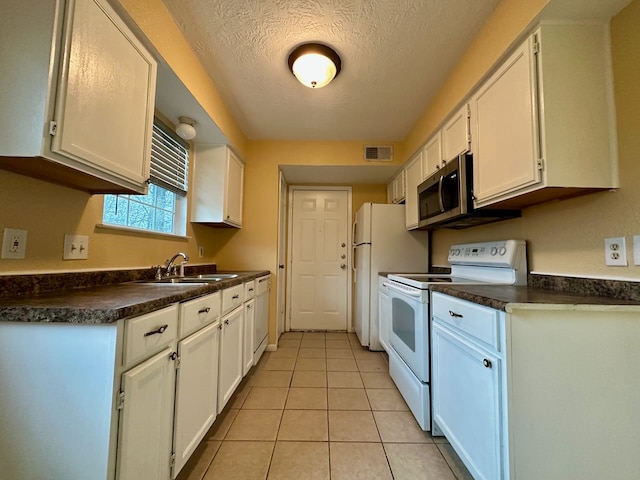 kitchen with light tile floors, a textured ceiling, white appliances, white cabinetry, and sink