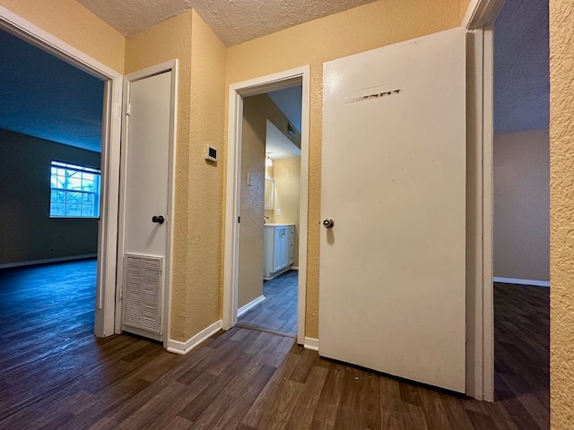 hallway featuring a textured ceiling and dark wood-type flooring