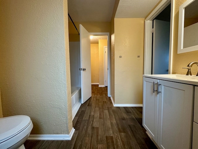 full bathroom featuring toilet, tub / shower combination, hardwood / wood-style floors, a textured ceiling, and vanity