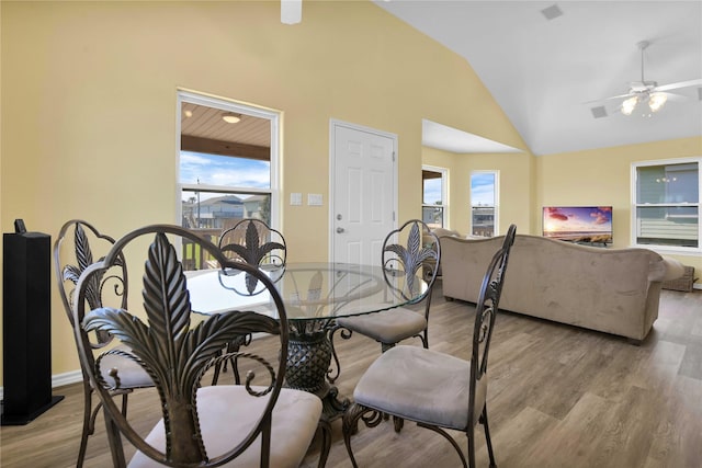 dining room with vaulted ceiling, plenty of natural light, and light wood-type flooring