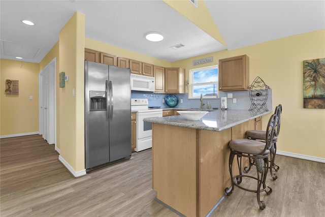 kitchen featuring tasteful backsplash, light hardwood / wood-style floors, and white appliances