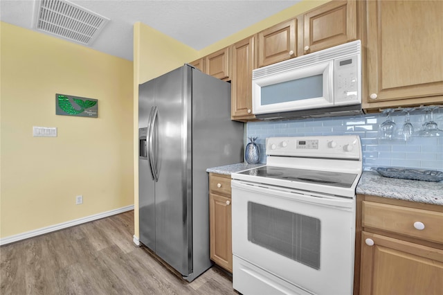 kitchen featuring white appliances, light stone countertops, backsplash, and light hardwood / wood-style flooring