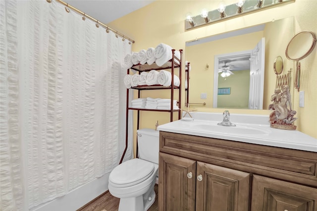 bathroom with vanity with extensive cabinet space, ceiling fan, toilet, and wood-type flooring