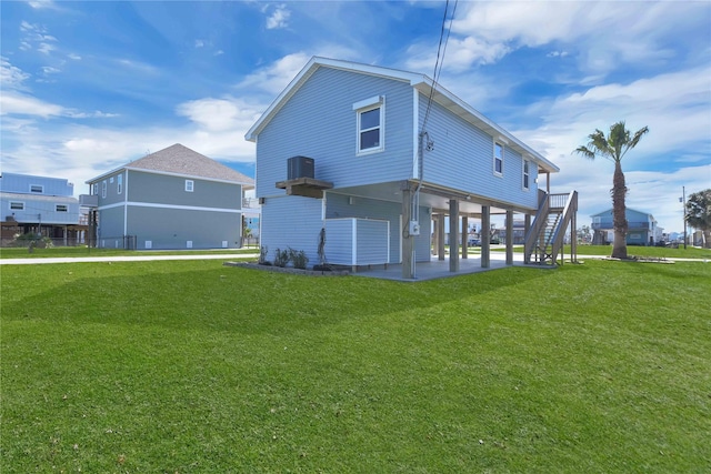 back of house with stairs, a patio area, central air condition unit, and a yard