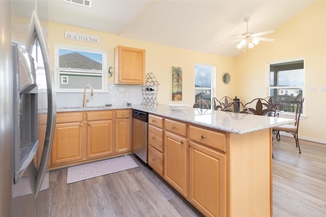 kitchen with a sink, light wood-style floors, stainless steel appliances, a peninsula, and lofted ceiling