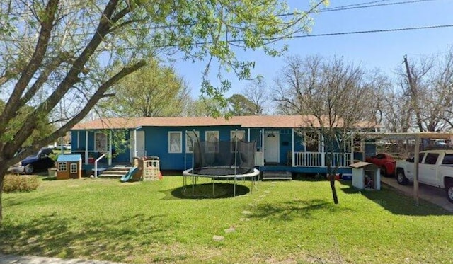 rear view of house featuring a lawn and a trampoline