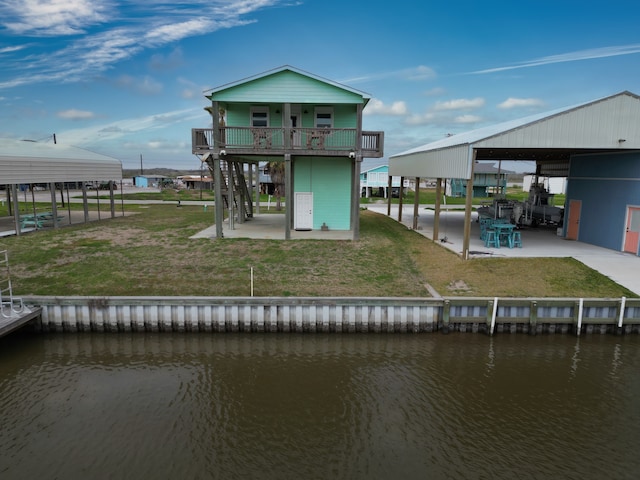 back of house featuring a water view, a patio area, a yard, and a balcony