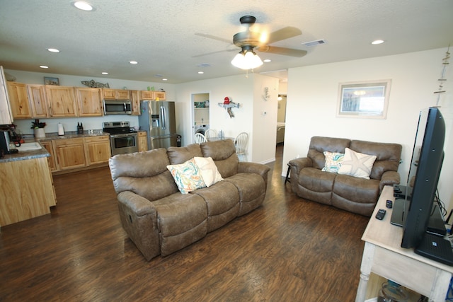 living room featuring dark hardwood / wood-style flooring, ceiling fan, sink, and a textured ceiling