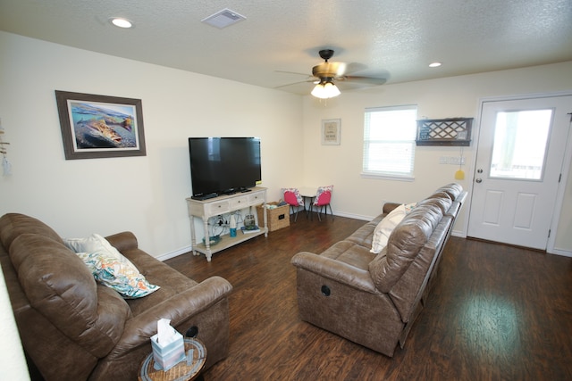 living room featuring ceiling fan, dark hardwood / wood-style floors, and a textured ceiling