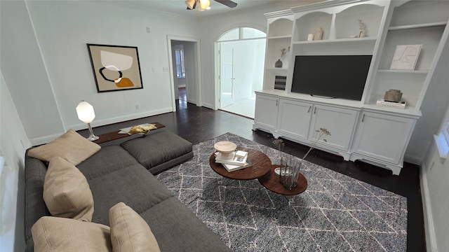 living room featuring built in features, ornamental molding, ceiling fan, and dark hardwood / wood-style flooring