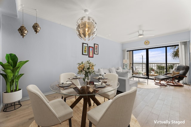 dining space with crown molding, light wood-type flooring, and ceiling fan with notable chandelier