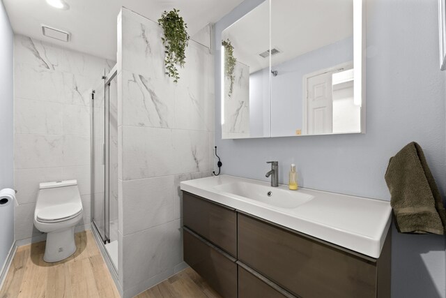 bathroom with tile walls, toilet, an enclosed shower, hardwood / wood-style floors, and vanity