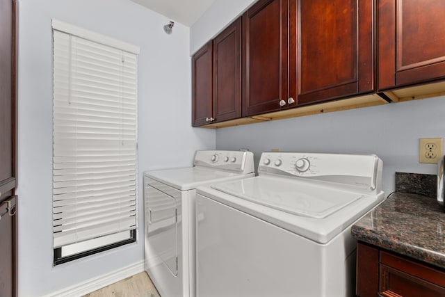 laundry area with washer and dryer, light hardwood / wood-style floors, and cabinets