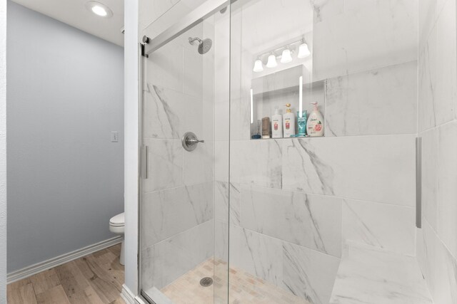 bathroom featuring an enclosed shower, toilet, and hardwood / wood-style flooring