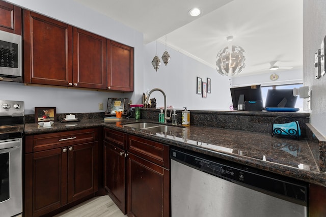 kitchen with pendant lighting, sink, dark stone counters, stainless steel appliances, and ceiling fan with notable chandelier