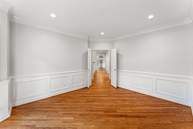 spare room with ornamental molding and light wood-type flooring