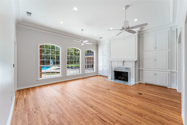 unfurnished living room with ceiling fan, light hardwood / wood-style flooring, a premium fireplace, and ornamental molding