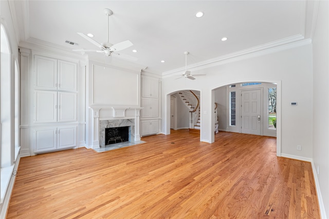 unfurnished living room featuring ornamental molding, a fireplace, ceiling fan, and light hardwood / wood-style floors