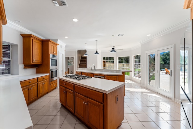 kitchen featuring an island with sink, crown molding, decorative light fixtures, and appliances with stainless steel finishes