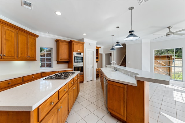 kitchen featuring pendant lighting, crown molding, a center island with sink, sink, and appliances with stainless steel finishes