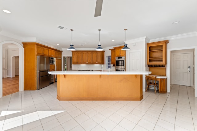 kitchen with hanging light fixtures, crown molding, appliances with stainless steel finishes, and a large island with sink