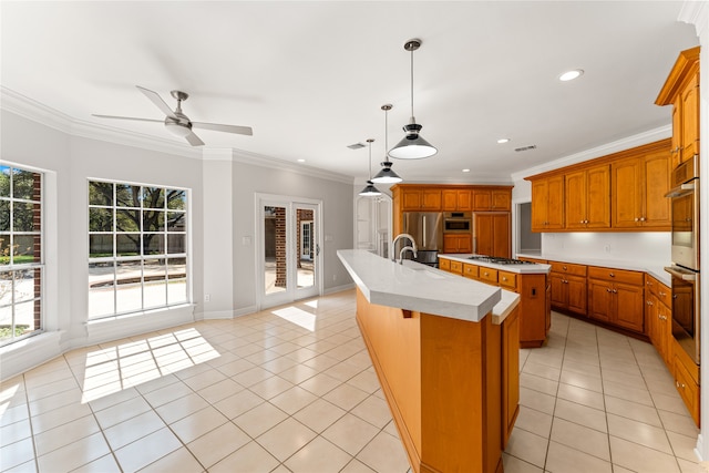 kitchen with ceiling fan, an island with sink, hanging light fixtures, light tile patterned floors, and crown molding