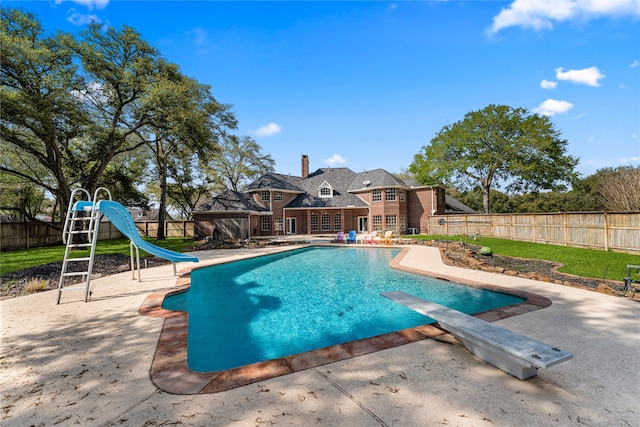 view of pool featuring a water slide, a diving board, and a patio area