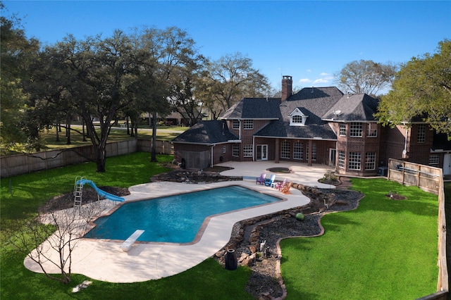 view of pool with a diving board, a lawn, a water slide, and a patio area