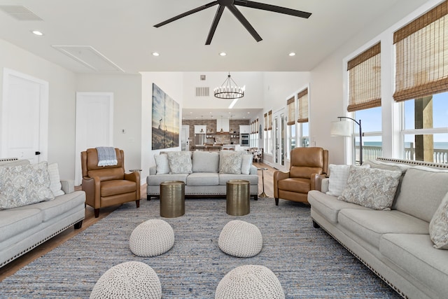 living room featuring a water view, dark hardwood / wood-style floors, and ceiling fan with notable chandelier