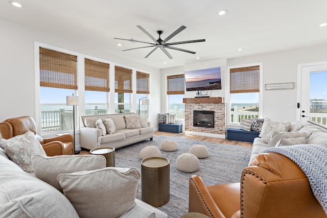 living room featuring a fireplace, wood-type flooring, and ceiling fan