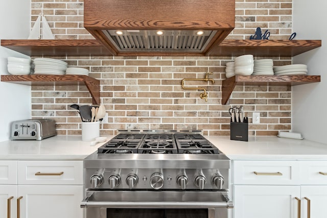 kitchen featuring stainless steel range with gas cooktop, white cabinetry, extractor fan, and decorative backsplash