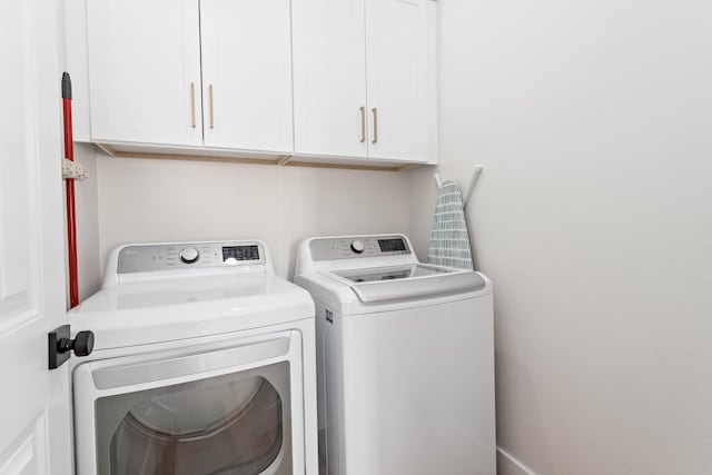 laundry area with washing machine and dryer and cabinets