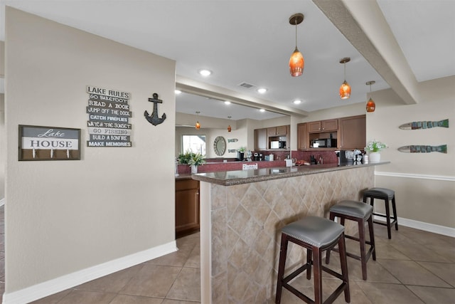 kitchen with decorative light fixtures, a breakfast bar area, kitchen peninsula, and light tile patterned floors