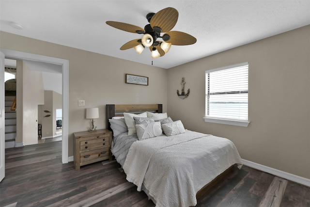 bedroom featuring dark wood-type flooring, a textured ceiling, and ceiling fan