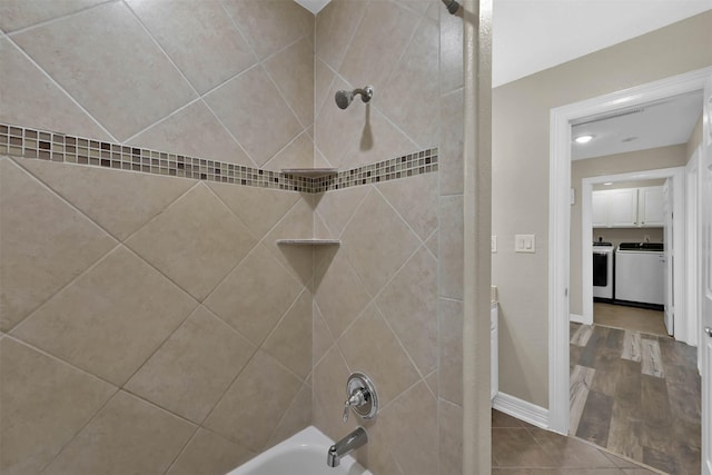 bathroom with washing machine and dryer and tiled shower / bath combo