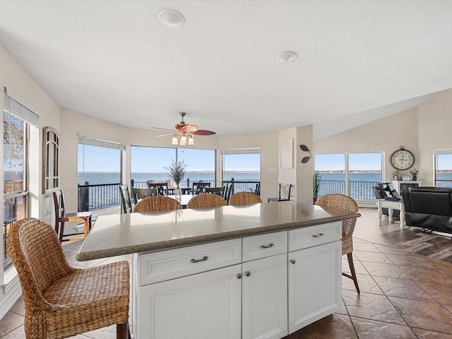 kitchen featuring white cabinets, a center island, ceiling fan, and a water view