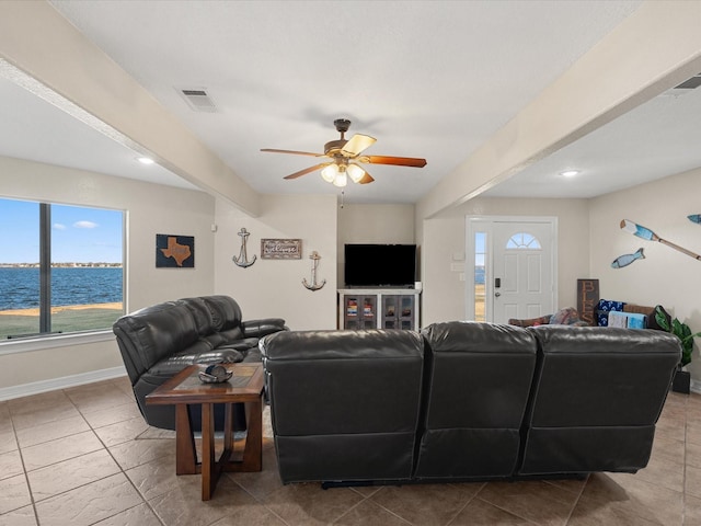 tiled living room featuring ceiling fan and a water view