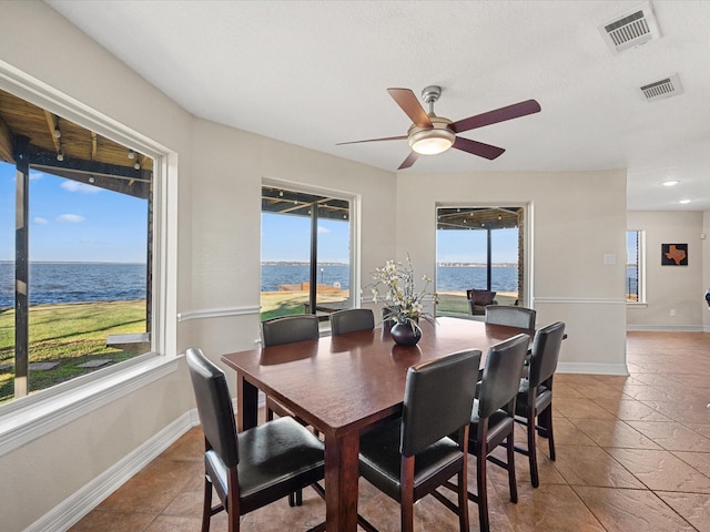 tiled dining area with ceiling fan and a water view