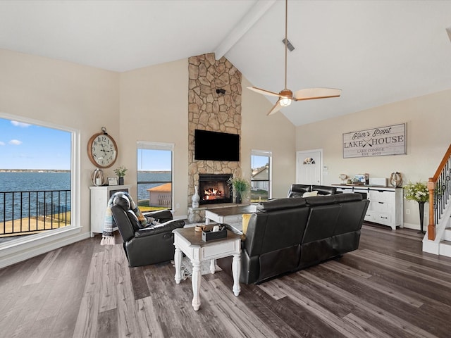 living room with hardwood / wood-style floors, a fireplace, ceiling fan, beamed ceiling, and a water view