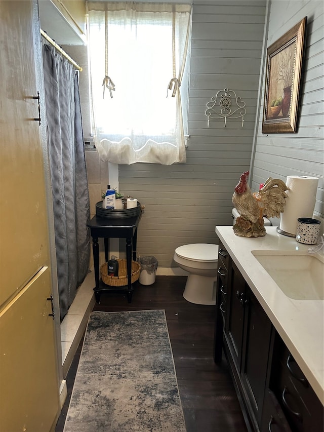 bathroom featuring toilet, wood walls, vanity, and hardwood / wood-style flooring