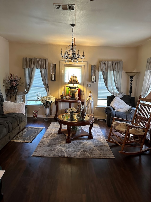 living room featuring plenty of natural light, dark hardwood / wood-style floors, and an inviting chandelier