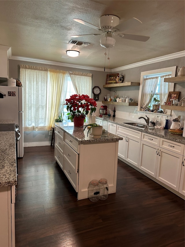 kitchen with light stone countertops, white cabinetry, dark hardwood / wood-style floors, and sink